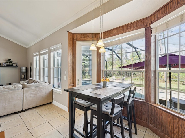 dining room with wooden walls, light tile patterned floors, lofted ceiling, a sunroom, and ornamental molding