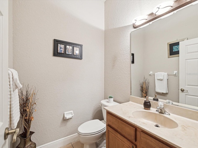 half bathroom featuring tile patterned flooring, toilet, vanity, and a textured wall