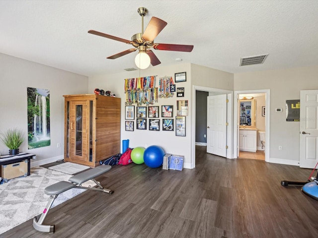 workout room with visible vents, a textured ceiling, wood finished floors, baseboards, and ceiling fan