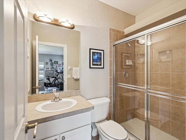 full bath featuring a shower stall, toilet, ensuite bathroom, a textured wall, and vanity