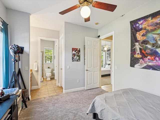 carpeted bedroom with tile patterned flooring, connected bathroom, baseboards, and ceiling fan