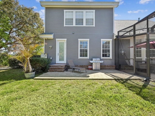 back of property with a yard, glass enclosure, and a patio area