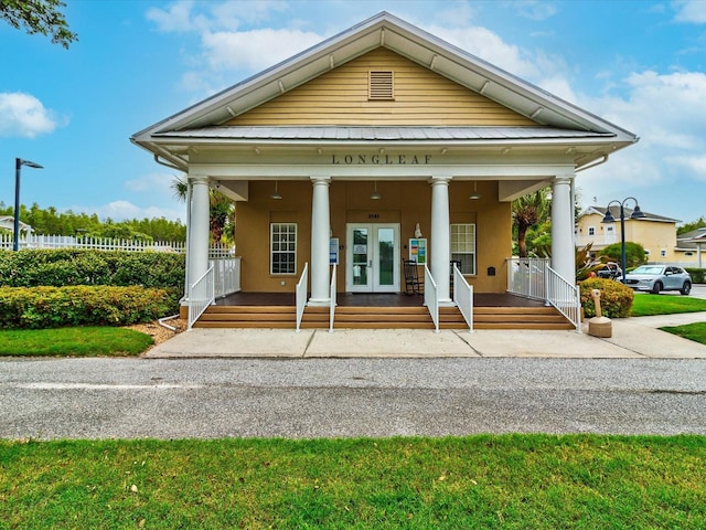 neoclassical home with french doors, covered porch, and stucco siding