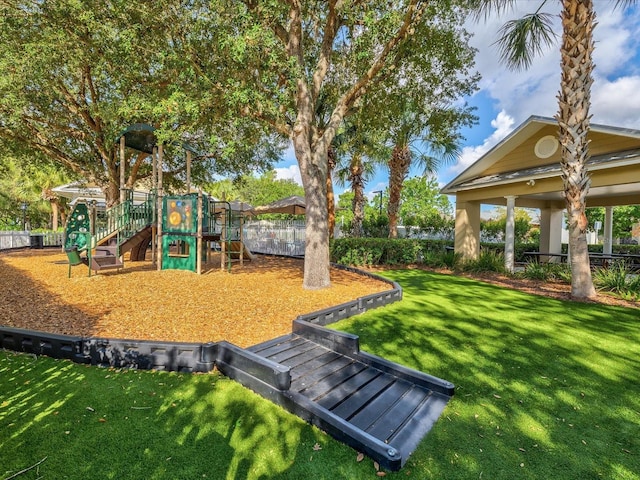 view of property's community with playground community, a lawn, and fence