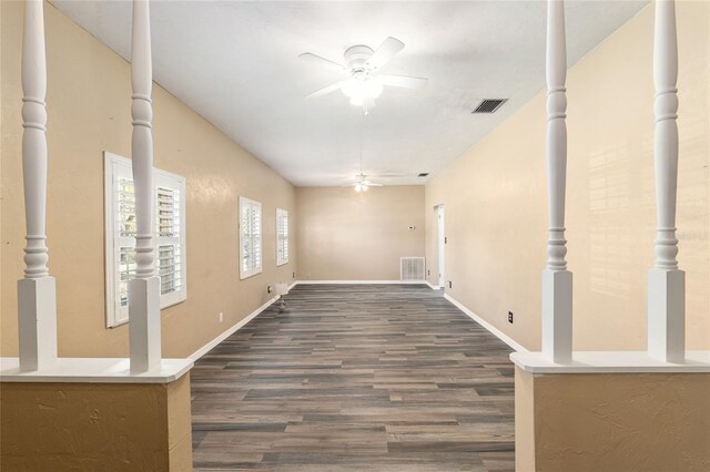 unfurnished room with baseboards, dark wood-style floors, visible vents, and ceiling fan