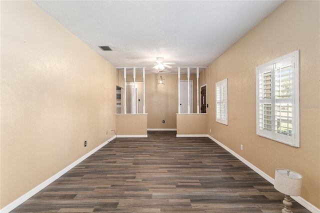 empty room with ceiling fan, visible vents, baseboards, and wood finished floors