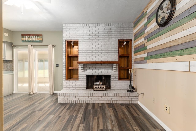 unfurnished living room featuring dark wood finished floors, a brick fireplace, and baseboards