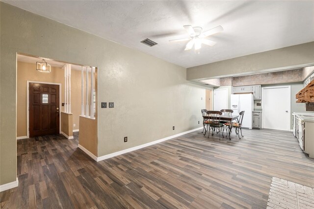 interior space with visible vents, white fridge with ice dispenser, ceiling fan, baseboards, and wood finished floors