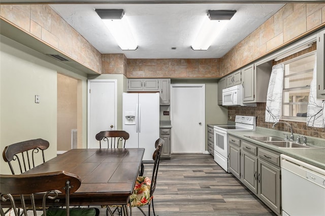 kitchen featuring backsplash, gray cabinets, wood finished floors, white appliances, and a sink