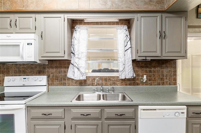 kitchen with white appliances, gray cabinetry, backsplash, and a sink