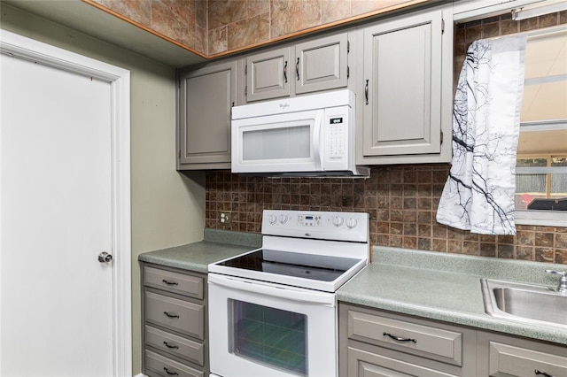 kitchen with white appliances, a sink, decorative backsplash, light countertops, and gray cabinetry