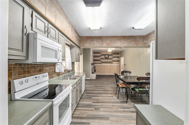 kitchen featuring a sink, white appliances, and gray cabinetry