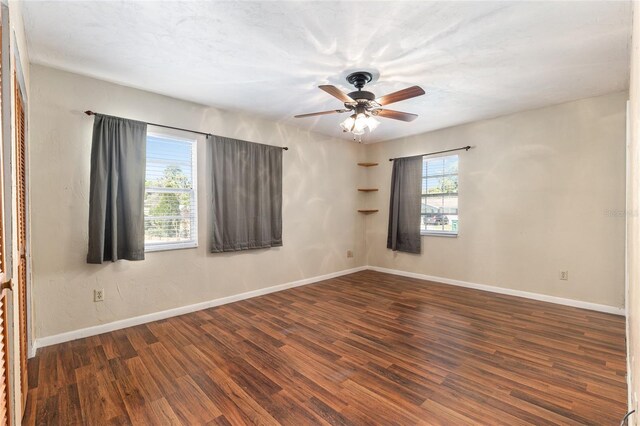 spare room featuring a ceiling fan, wood finished floors, baseboards, and a healthy amount of sunlight