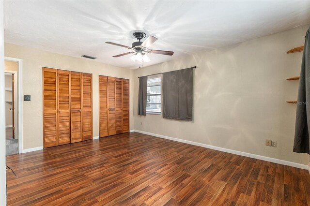 unfurnished bedroom with visible vents, baseboards, multiple closets, and wood finished floors