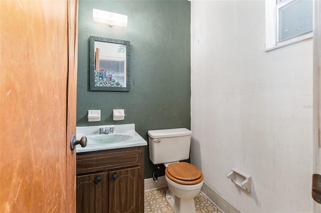 half bath with vanity, toilet, and baseboards