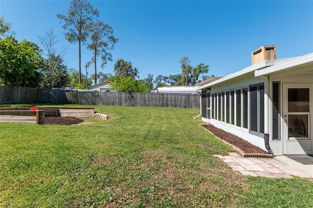 view of yard featuring a vegetable garden, a fenced backyard, and a sunroom