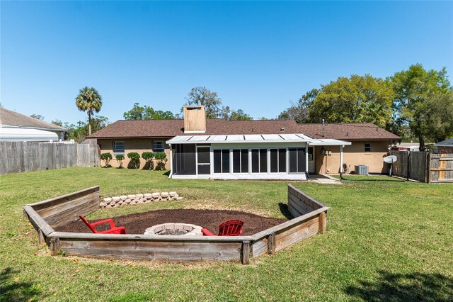 back of house with a fire pit, central AC unit, a chimney, a fenced backyard, and a sunroom