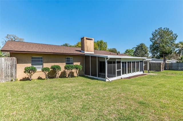 back of property featuring a yard, stucco siding, a chimney, and fence