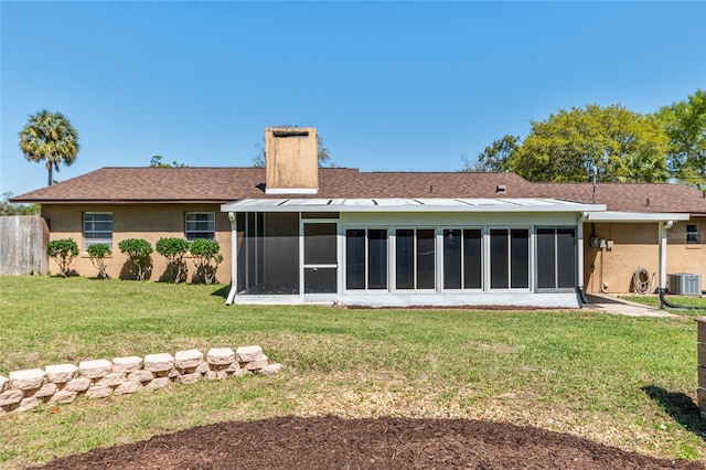 back of property featuring cooling unit, a sunroom, stucco siding, a chimney, and a lawn