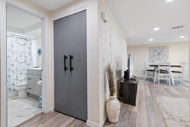 corridor featuring recessed lighting, visible vents, baseboards, and light wood finished floors