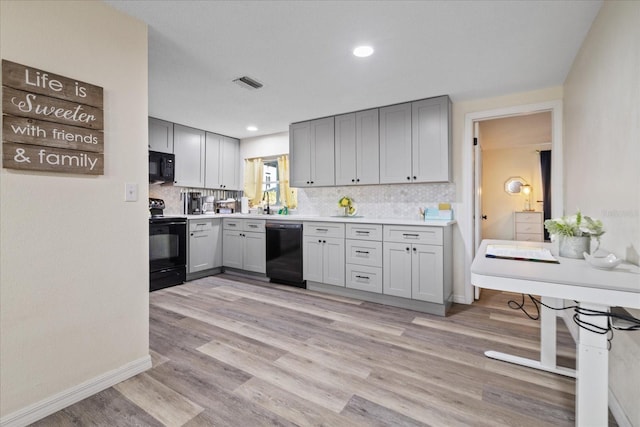 kitchen with backsplash, visible vents, gray cabinets, and black appliances