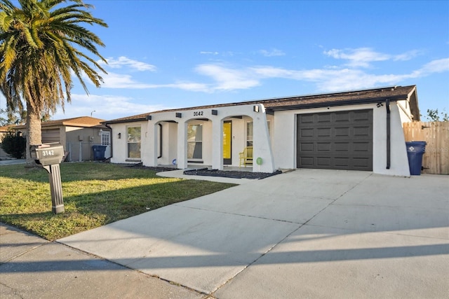 view of front of home with stucco siding, driveway, fence, a front yard, and a garage