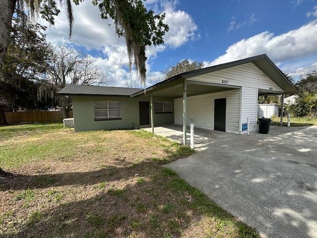 back of property featuring a carport, concrete driveway, and fence