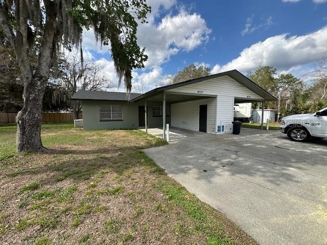 single story home featuring a carport, concrete driveway, a front lawn, and fence