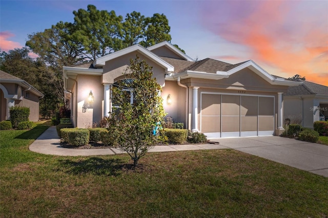 ranch-style house with stucco siding, driveway, a front yard, and an attached garage