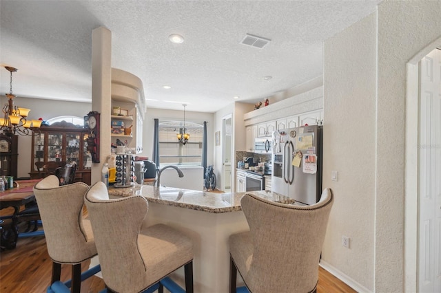 kitchen featuring a chandelier, stainless steel appliances, a wealth of natural light, and wood finished floors