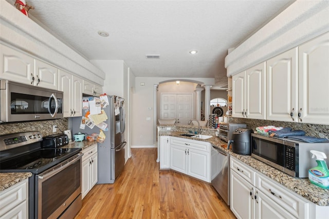 kitchen with visible vents, a sink, backsplash, stainless steel appliances, and ornate columns