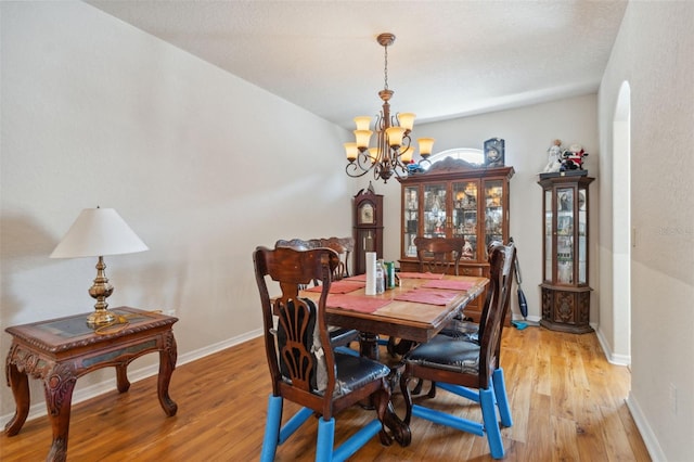dining room featuring a notable chandelier, baseboards, and light wood-style floors