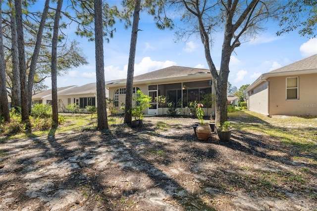 rear view of property with stucco siding and a sunroom
