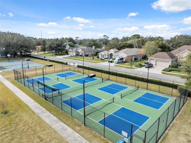 view of tennis court with a residential view and fence