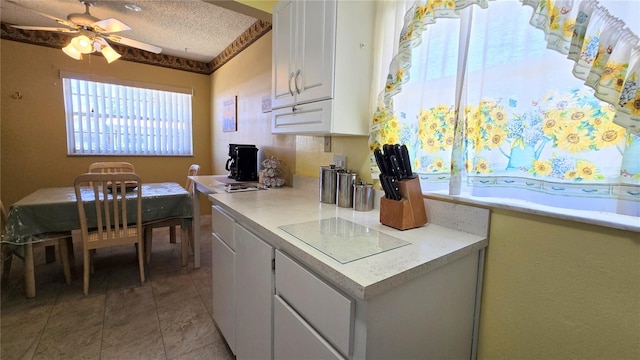 kitchen with a textured ceiling, white cabinetry, light countertops, and ceiling fan