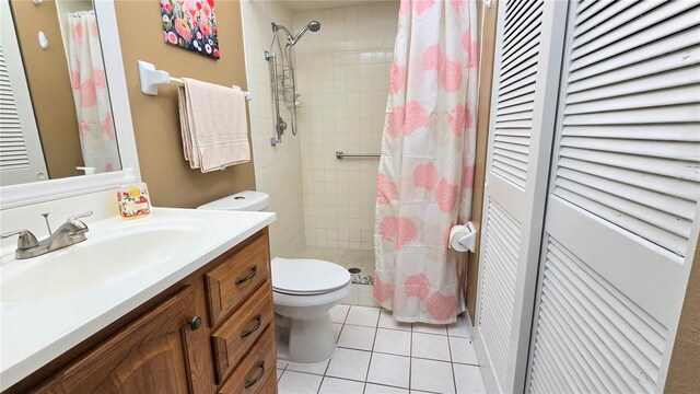 bathroom featuring toilet, a closet, a shower stall, tile patterned flooring, and vanity