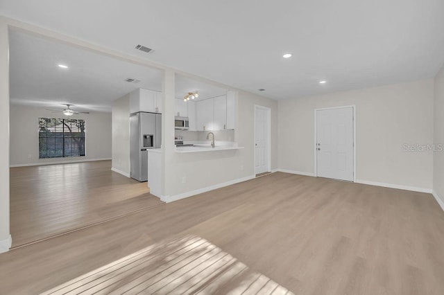 unfurnished living room featuring baseboards, visible vents, and light wood-type flooring