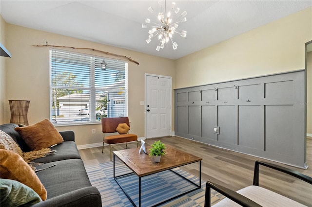 living room featuring light wood finished floors, a notable chandelier, and baseboards