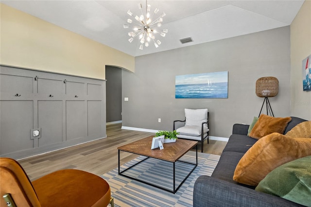 living room featuring a notable chandelier, visible vents, light wood-style flooring, and arched walkways