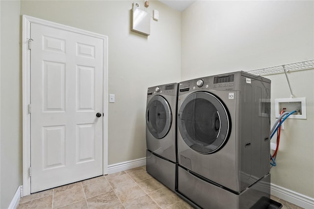 washroom featuring laundry area, baseboards, and separate washer and dryer