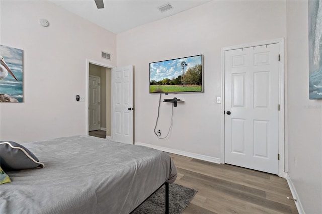 bedroom featuring a ceiling fan, wood finished floors, visible vents, and baseboards