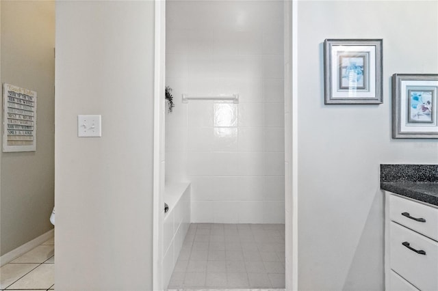 bathroom featuring vanity, baseboards, a shower, tile patterned floors, and a washtub