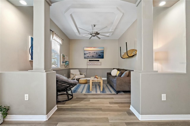 interior space featuring ceiling fan, baseboards, ornate columns, and wood finished floors