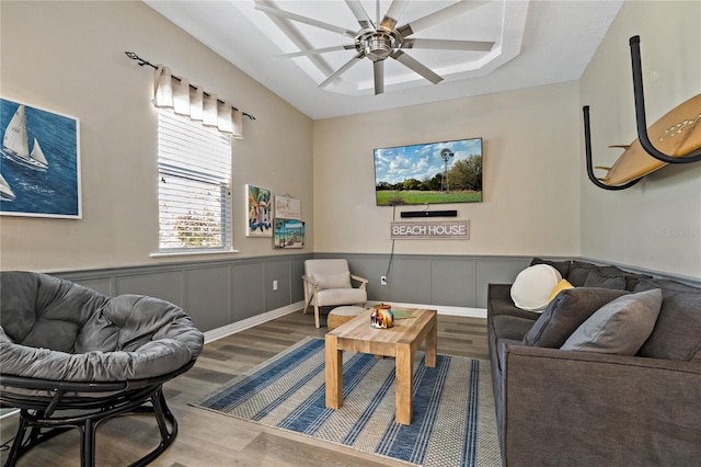 living room with ceiling fan, a wainscoted wall, and wood finished floors