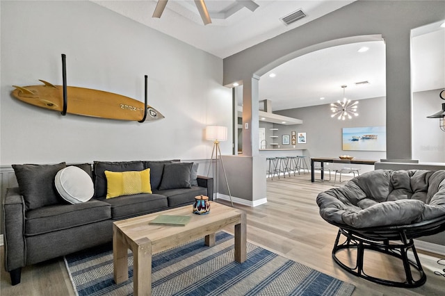 living area with arched walkways, visible vents, light wood-style flooring, and baseboards