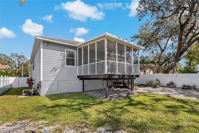 back of property featuring a fenced backyard, a yard, and a sunroom