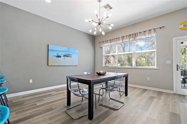 dining space with light wood-type flooring, baseboards, visible vents, and a notable chandelier