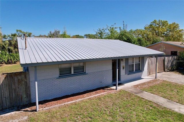 single story home with covered porch, fence, brick siding, and metal roof