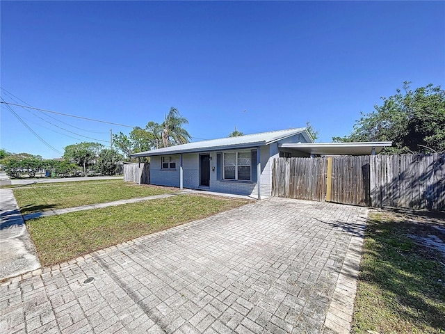 view of front of house with a front yard, decorative driveway, fence, and metal roof