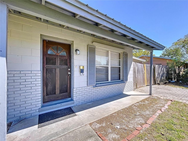 doorway to property with fence and brick siding